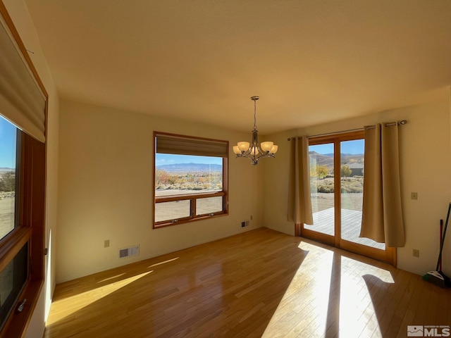 unfurnished dining area with a mountain view, wood-type flooring, and a chandelier