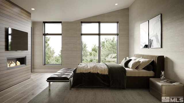 bedroom featuring lofted ceiling, multiple windows, hardwood / wood-style flooring, and a large fireplace