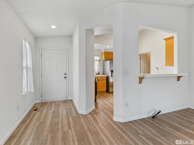 foyer entrance featuring vaulted ceiling and light hardwood / wood-style floors