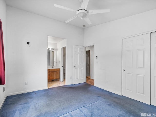 unfurnished bedroom with a closet, ensuite bathroom, light colored carpet, and ceiling fan