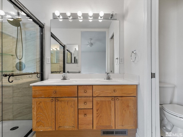 bathroom featuring a shower with door, vanity, and toilet