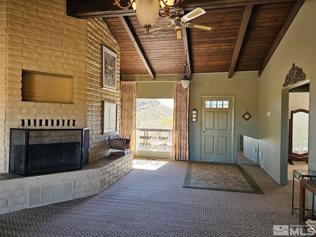 carpeted entryway featuring wood ceiling, ceiling fan, beamed ceiling, an outdoor brick fireplace, and a mountain view