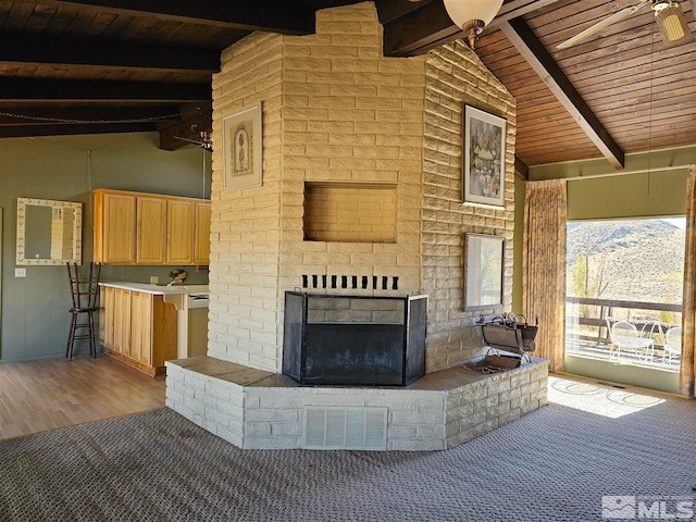 unfurnished living room featuring an outdoor brick fireplace, lofted ceiling with beams, light hardwood / wood-style floors, wooden ceiling, and a mountain view