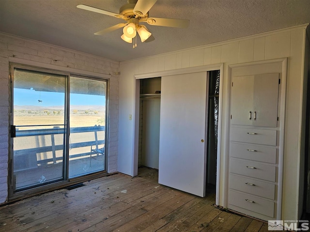 unfurnished bedroom featuring a closet, ceiling fan, hardwood / wood-style flooring, and access to outside