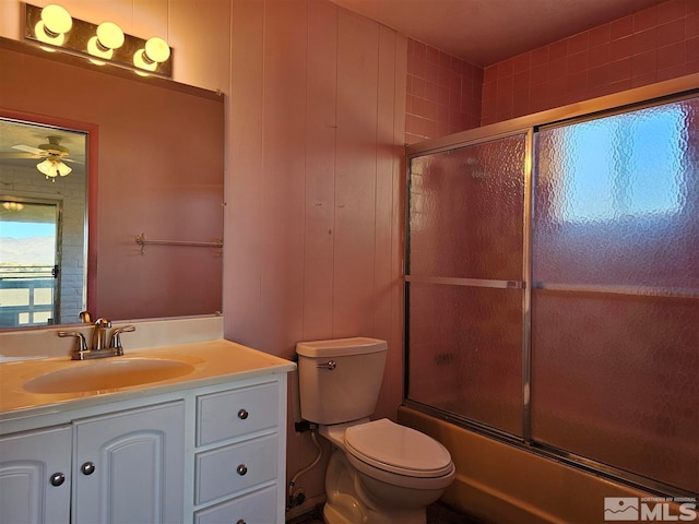 full bathroom with ceiling fan, combined bath / shower with glass door, toilet, vanity, and wooden walls