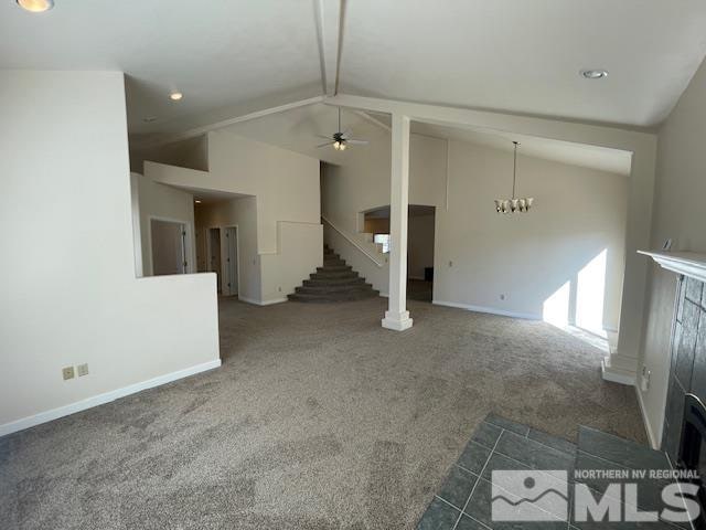 unfurnished living room with dark carpet, vaulted ceiling, and ceiling fan with notable chandelier