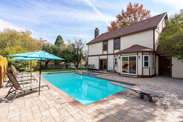 view of swimming pool featuring a diving board, a patio, and an in ground hot tub