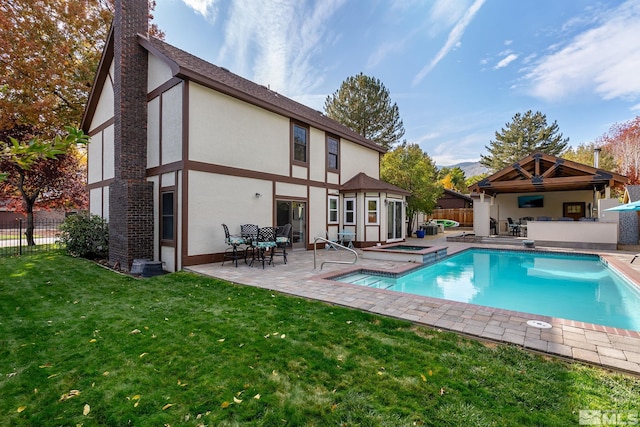 back of property featuring a swimming pool with hot tub, a patio, and a yard