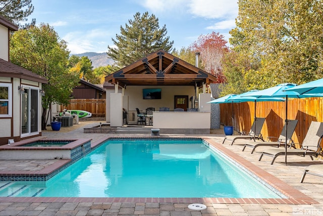 rear view of property with a mountain view, cooling unit, a patio, and a pool with hot tub