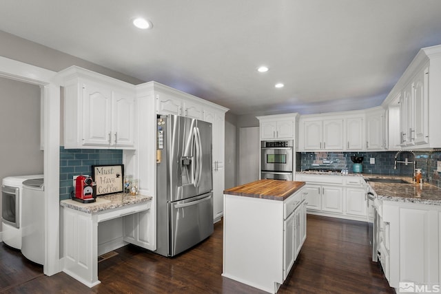 kitchen with stainless steel appliances, washer and dryer, white cabinets, and a kitchen island