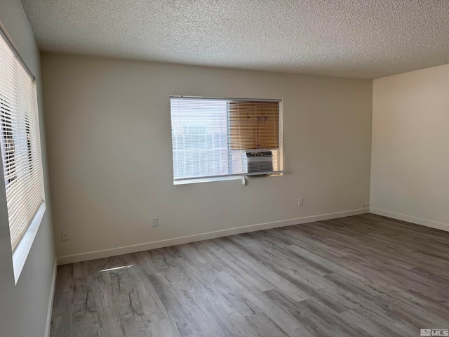 empty room featuring a textured ceiling, a healthy amount of sunlight, and light hardwood / wood-style flooring