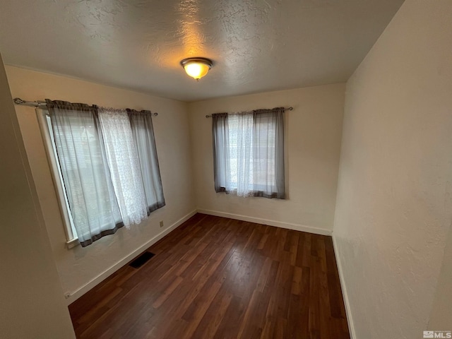 spare room with dark wood-type flooring and a textured ceiling