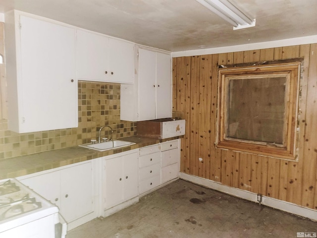 kitchen featuring sink, wood walls, white cabinets, and white gas range oven