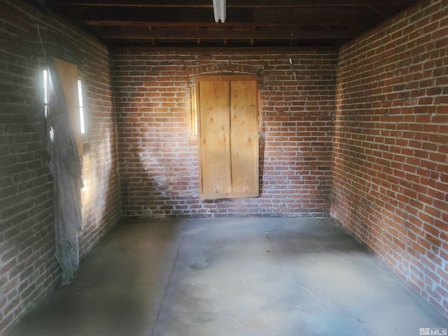 spare room featuring concrete floors and brick wall