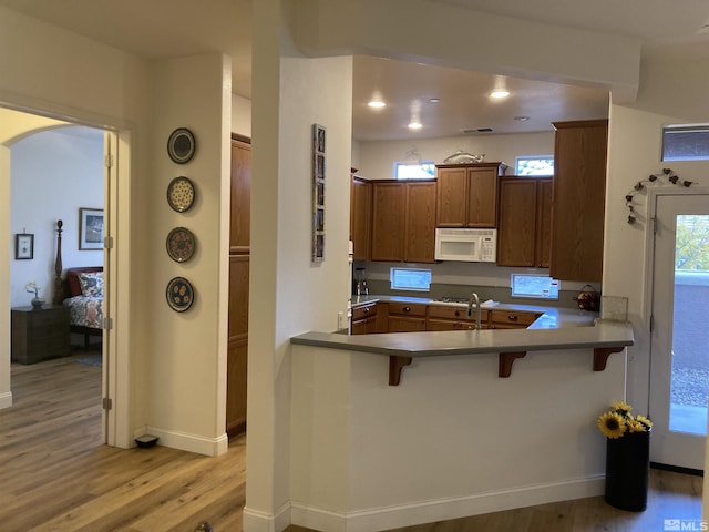 kitchen featuring kitchen peninsula, sink, a kitchen breakfast bar, and light hardwood / wood-style flooring