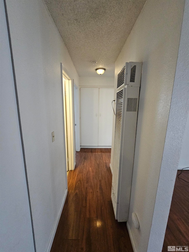 hallway featuring a textured ceiling and dark hardwood / wood-style flooring