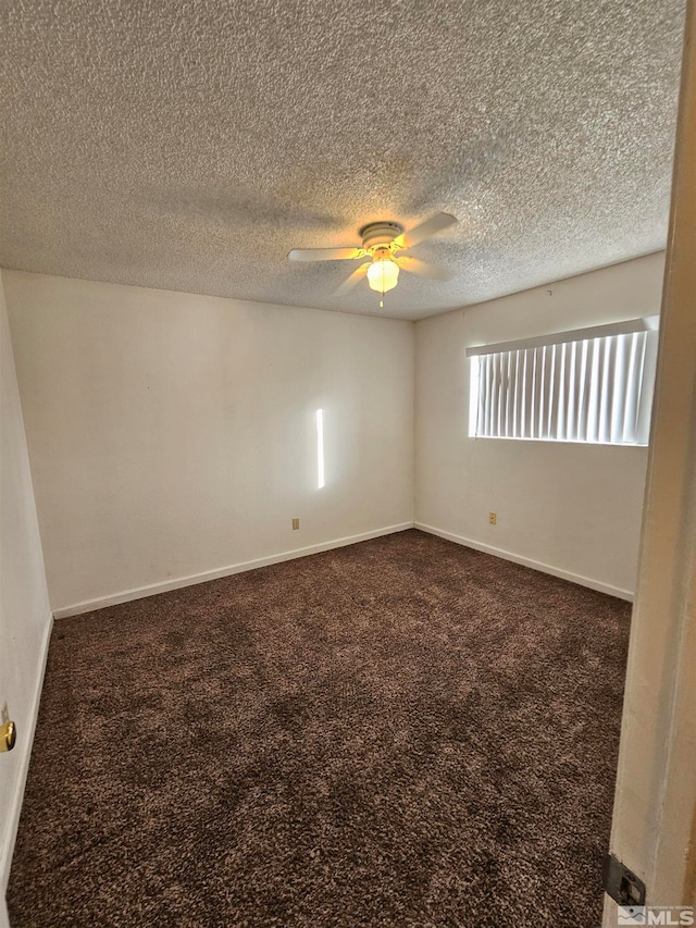 empty room featuring a textured ceiling, dark colored carpet, and ceiling fan