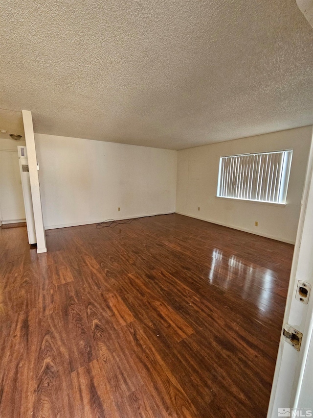 unfurnished room with dark wood-type flooring and a textured ceiling