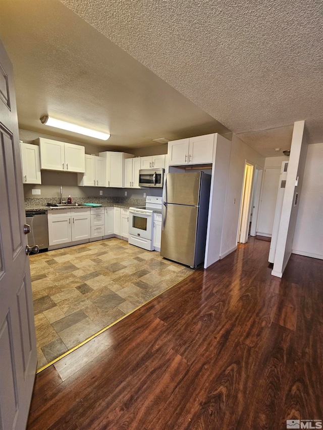 kitchen with stainless steel appliances, white cabinets, sink, and a textured ceiling