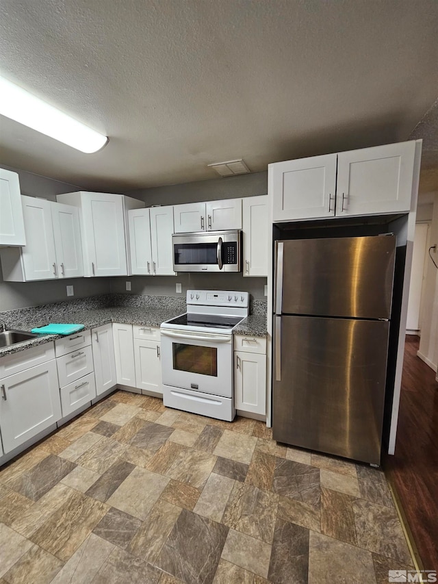 kitchen with appliances with stainless steel finishes, a textured ceiling, and white cabinets