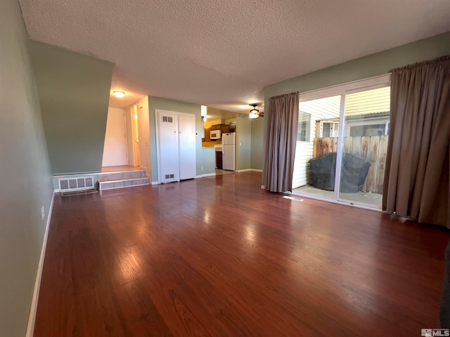 unfurnished living room featuring ceiling fan, a textured ceiling, and dark hardwood / wood-style floors