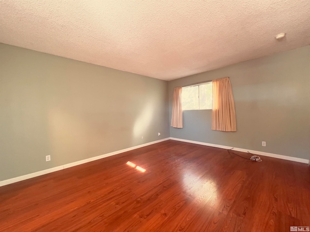 spare room with dark hardwood / wood-style flooring and a textured ceiling