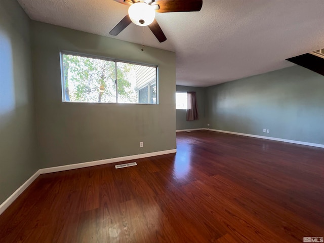 empty room with dark hardwood / wood-style flooring, a textured ceiling, and ceiling fan