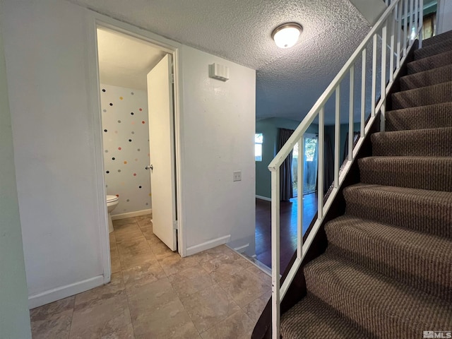 staircase featuring a textured ceiling