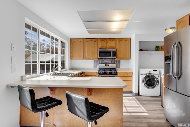 kitchen with stainless steel appliances, a kitchen breakfast bar, kitchen peninsula, and washer / clothes dryer