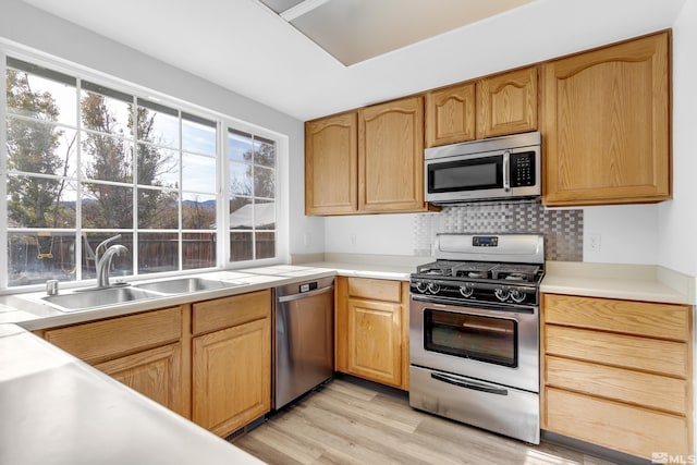 kitchen featuring backsplash, sink, light hardwood / wood-style flooring, and appliances with stainless steel finishes