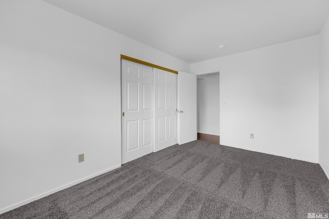 unfurnished bedroom featuring a closet and dark carpet