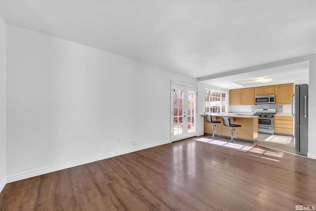 unfurnished living room with dark hardwood / wood-style floors and french doors