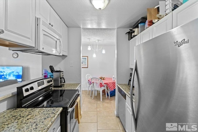 kitchen with white cabinets, light stone countertops, a textured ceiling, appliances with stainless steel finishes, and light tile patterned flooring