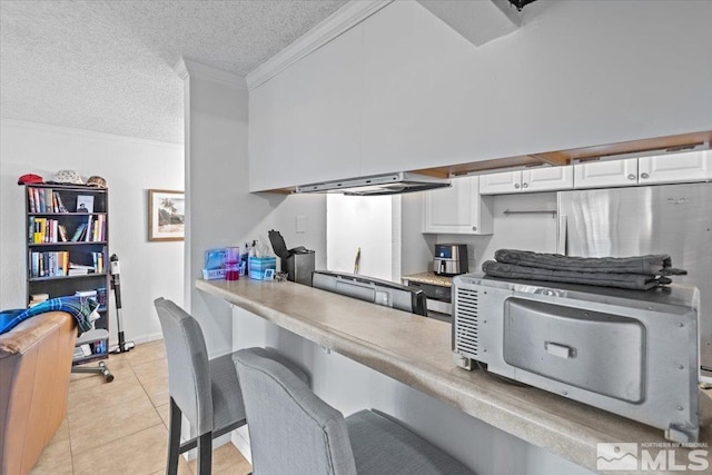 kitchen featuring white cabinets, light tile patterned floors, a textured ceiling, and range hood