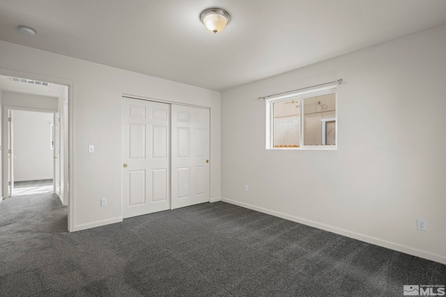 unfurnished bedroom with dark colored carpet and a closet