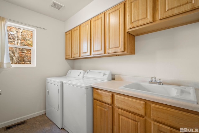 clothes washing area with separate washer and dryer, cabinets, and sink