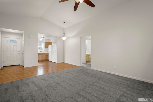 unfurnished living room with ceiling fan, vaulted ceiling, and light hardwood / wood-style floors