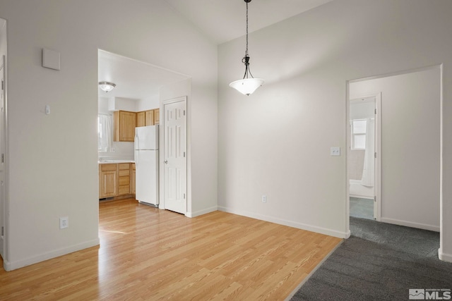 spare room featuring light wood-type flooring and vaulted ceiling