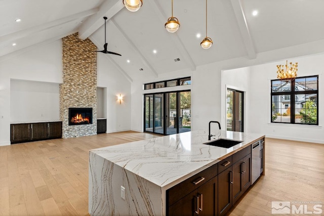 kitchen with a kitchen island with sink, high vaulted ceiling, light hardwood / wood-style floors, and sink