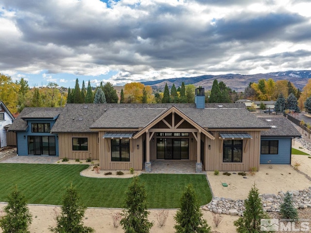 back of property featuring a mountain view, a patio, and a yard