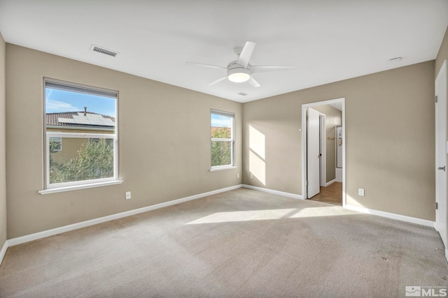 unfurnished bedroom with light carpet, multiple windows, and ceiling fan