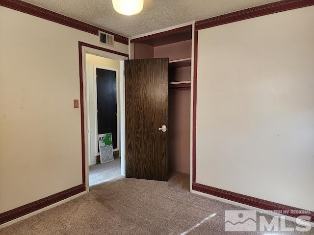 unfurnished bedroom with a textured ceiling, a closet, carpet floors, and crown molding