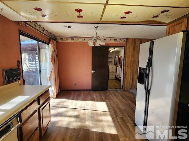 kitchen with pendant lighting, light hardwood / wood-style floors, a chandelier, and white refrigerator with ice dispenser