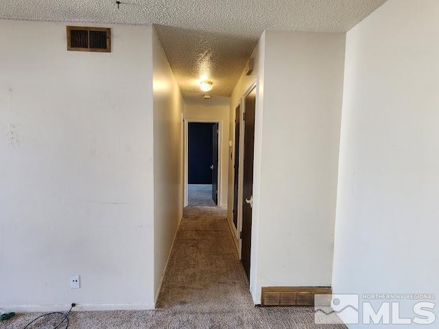 hallway featuring a textured ceiling and carpet