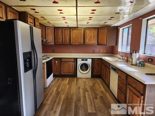 kitchen featuring exhaust hood, dark hardwood / wood-style flooring, washer / clothes dryer, sink, and white appliances