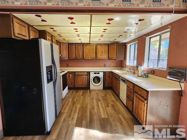 kitchen with washer / clothes dryer, light wood-type flooring, sink, and stainless steel appliances