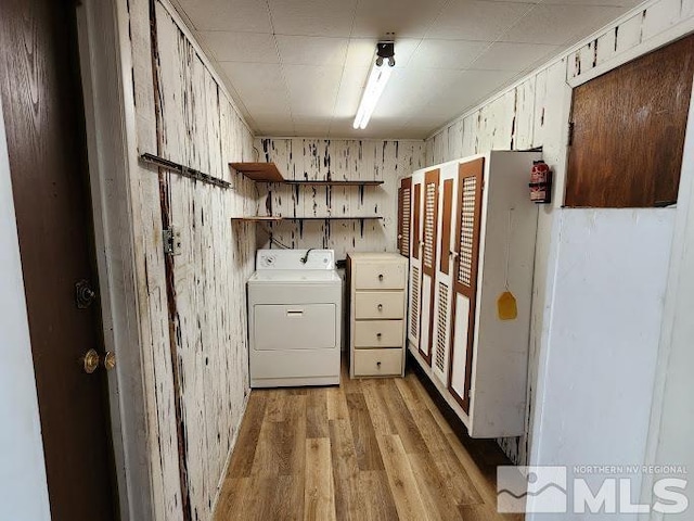 washroom with washer / clothes dryer, wooden walls, and light hardwood / wood-style floors