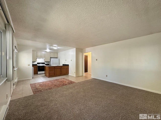 kitchen featuring white appliances, a textured ceiling, light colored carpet, and a center island