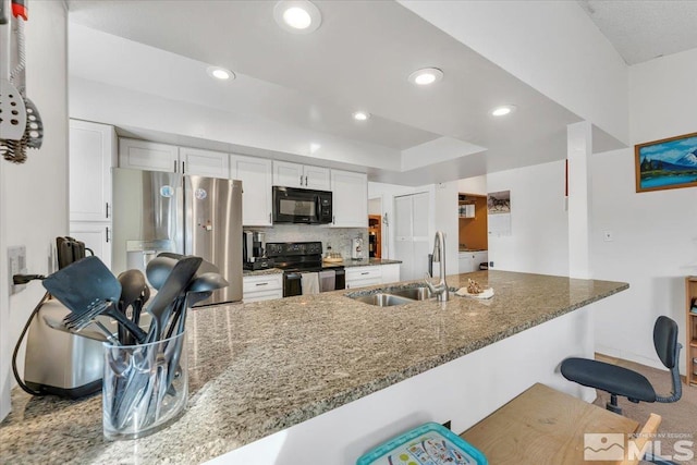 kitchen featuring decorative backsplash, black appliances, a kitchen breakfast bar, white cabinetry, and dark stone countertops