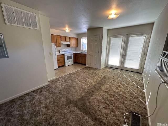 kitchen featuring a textured ceiling, light carpet, white appliances, and sink